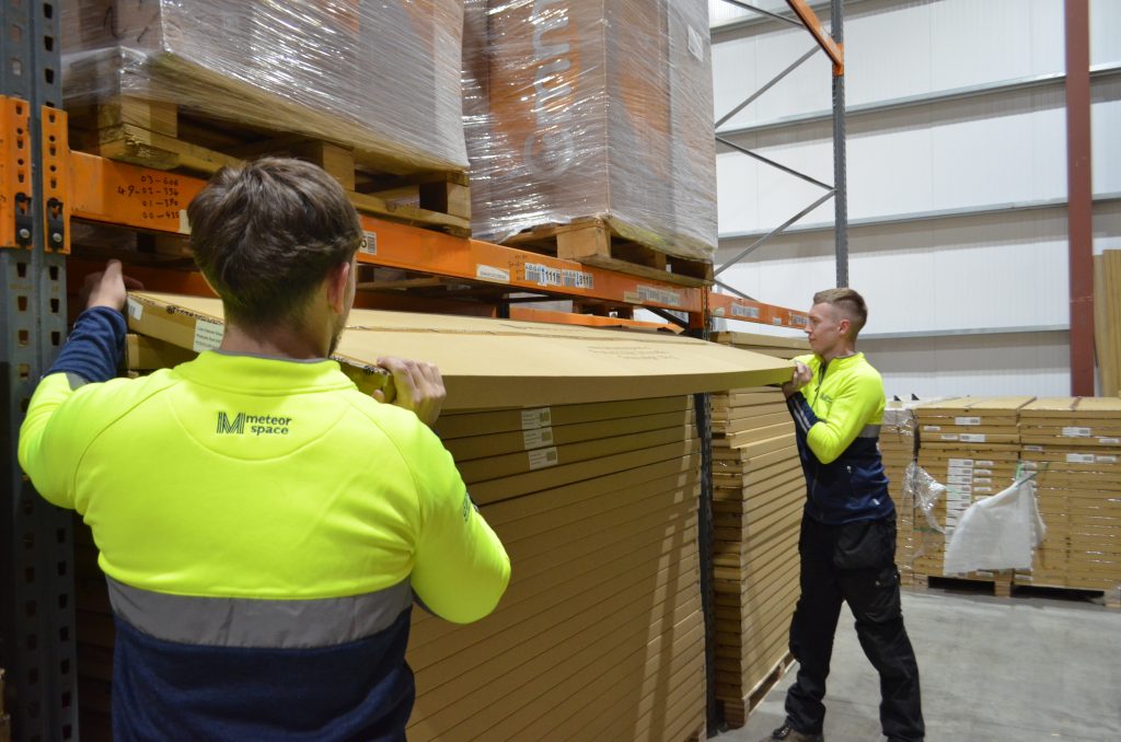 Meteor Space 2-man delivery team carefully handling bulky furniture item inside secure warehouse