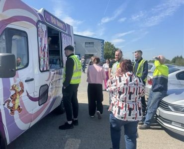 Meteor Space team gathered outside around the ice cream van during a sunny workday.