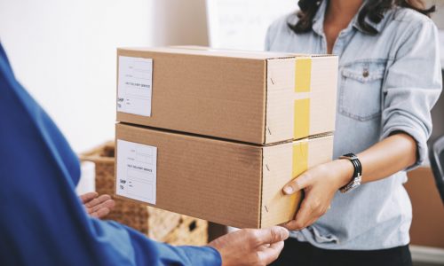 Female delivery service manager giving packages to courier